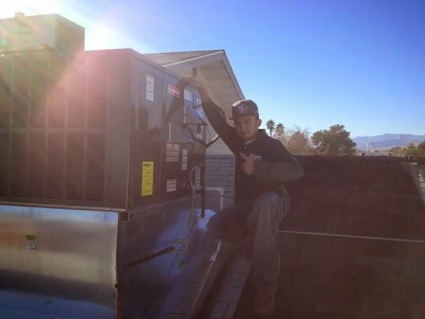 HVAC technician performing AC Tune-Up on a rooftop unit in De Pere